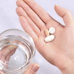 pills and glass of water in hands